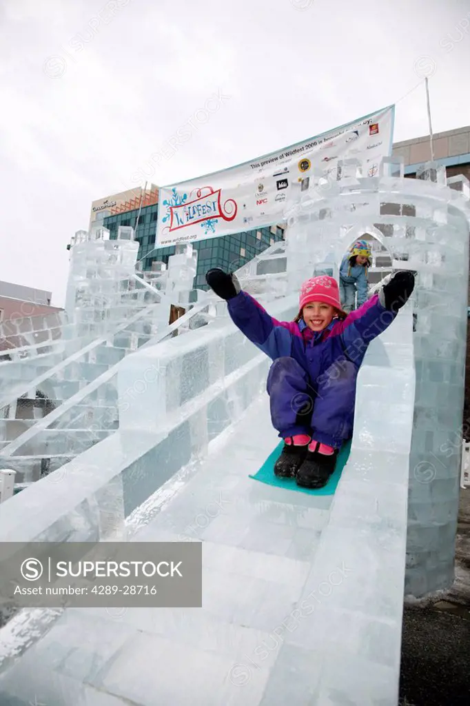Young girl slides down an ice castle slide in downtown Anchorage, Southcentral Alaska