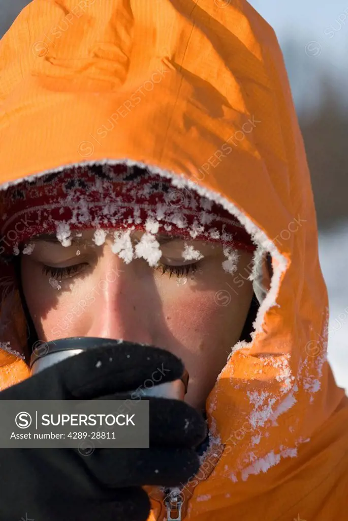 Close up of adult woman drinking hot drink frosty from 30 below zero weather within White Mountain National Recreation Area winter Interior Alaska