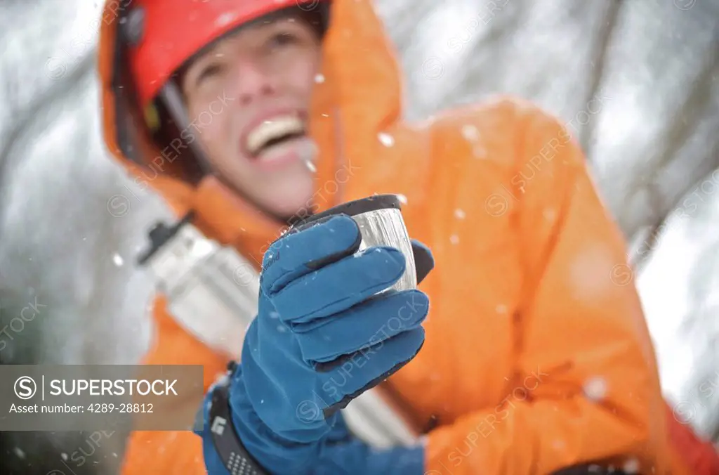Female ice climber enjoys a hot drink during a day of ice climbing in Portage Valley, Chugach National Forest of Southcentral Alaska
