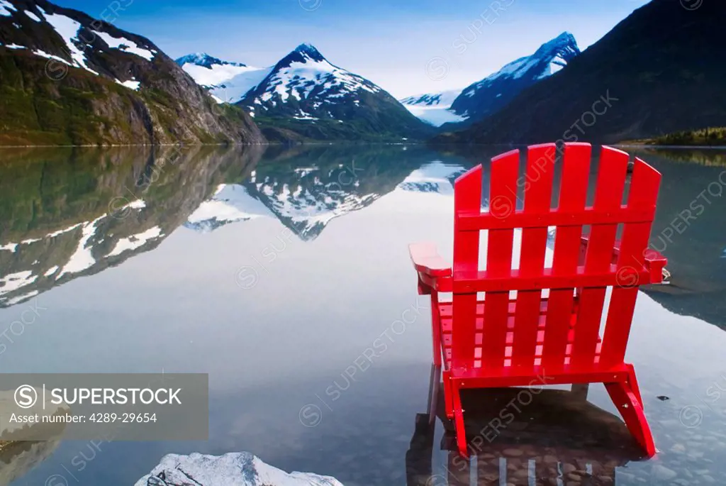 Red Adirondack chair at Portage Lake with Chugach Mountains in the background, Southcentral, Alaska