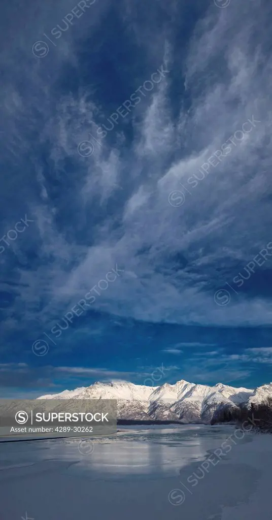 Cirrus clouds loom over an icy Knik River and snow covered Talkeetna Mountains in Knik River Valley near Knik River Bridge, Matanuska Susitna Valley, ...