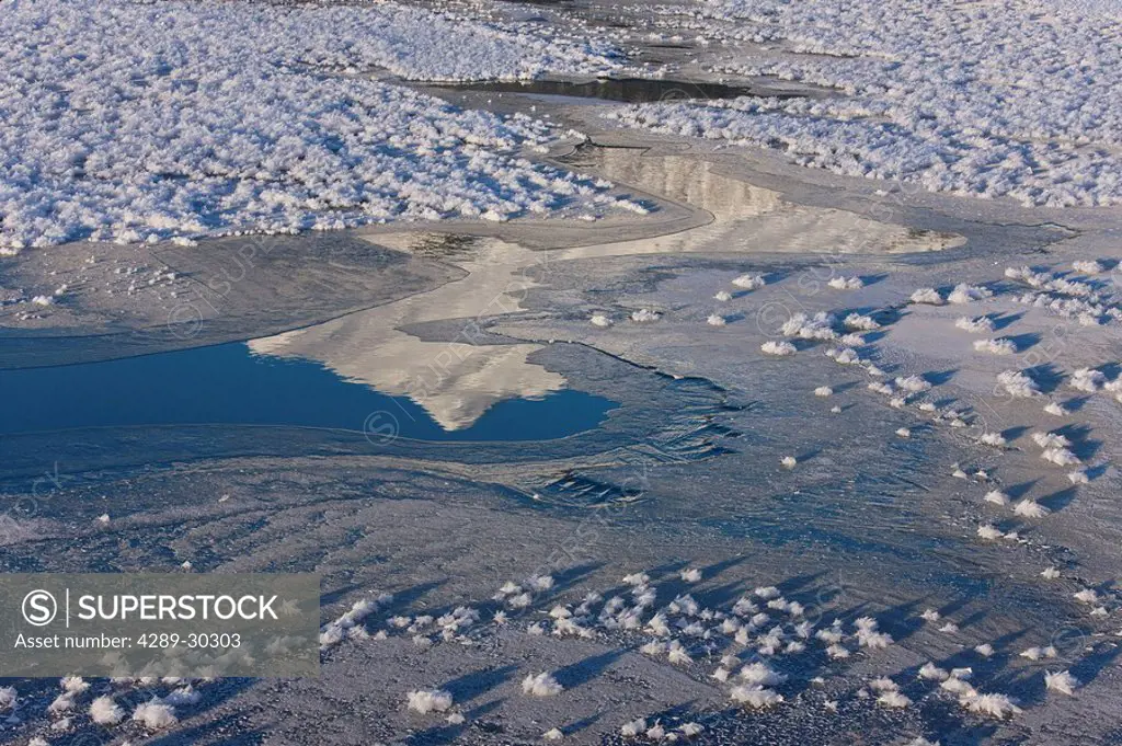 Snowy mountain peak is reflected in a bit of open water as the hoar frost encrusted ice freezes over open water, Southeast Alaska