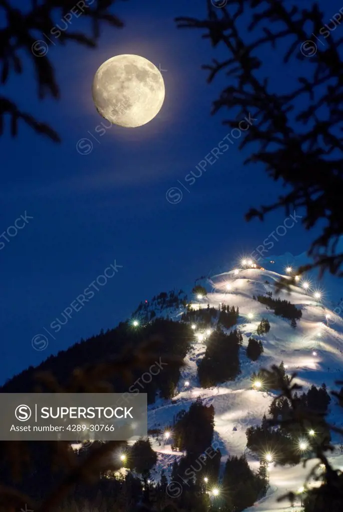 Winter moonrise over Mt. Alyeska during the annual Torchlight Parade, Girdwood, Southcentral Alaska, Winter, COMPOSITE