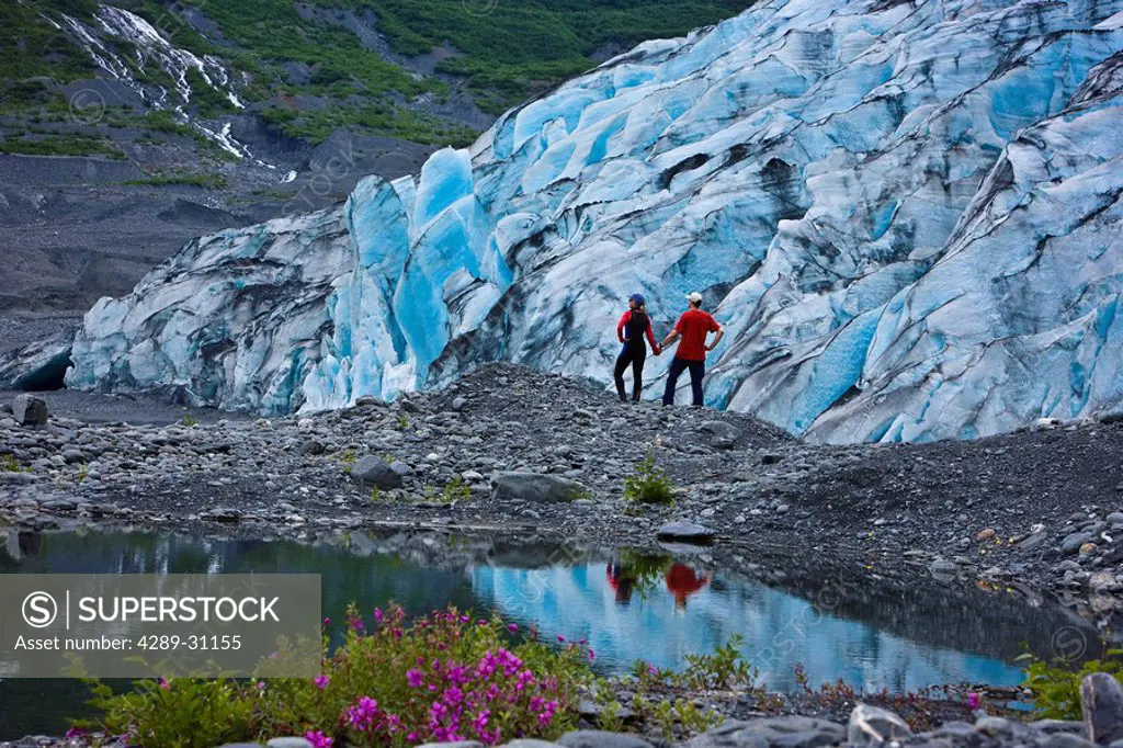 Hiking couple explore the newly exposed ground next to Shoup Glacier, Shoup Bay State Marine Park, Prince William Sound, Southcentral Alaska