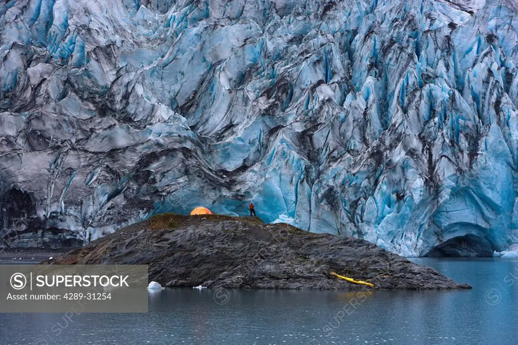 Kayaker with his boat pulled up on an island in front of Shoup Glacier, Shoup Bay State Marine Park, Prince William Sound, Southcentral Alaska