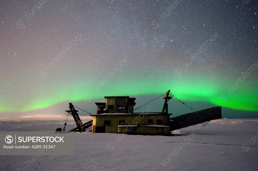 Green Northern Lights dance over a historical gold dredge near Nome, Alaska
