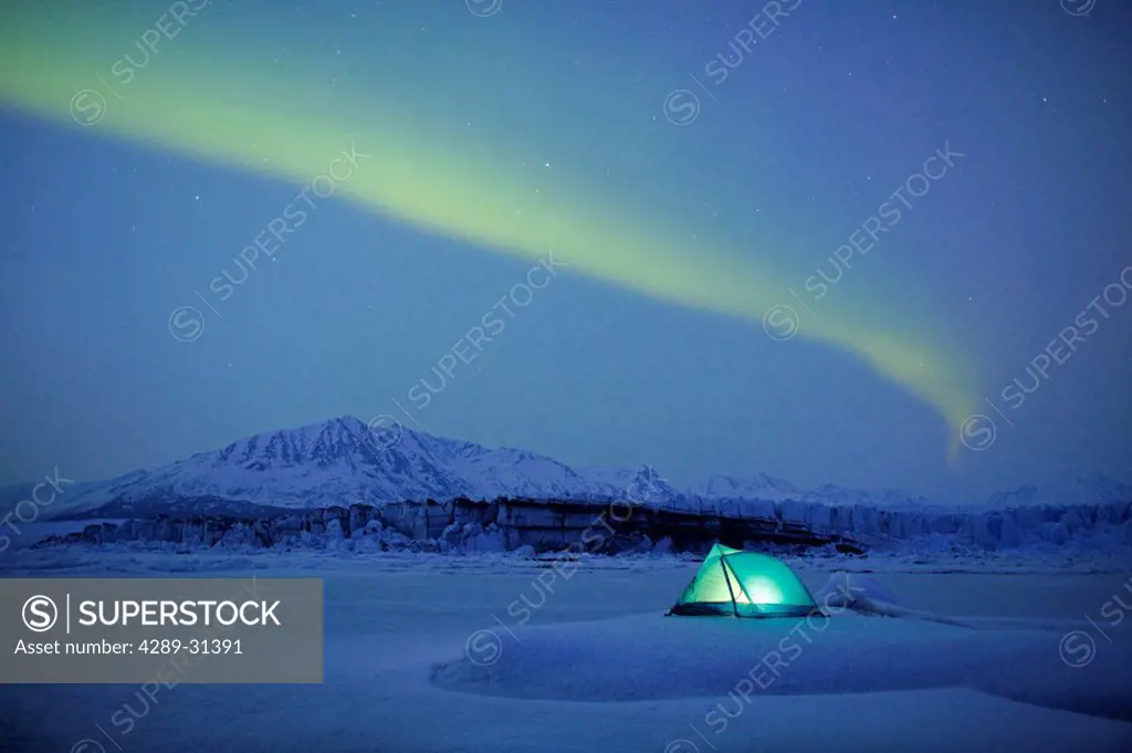 Northern Lights over lit tent on Knik Glacier, Southcentral, Alaska, Winter