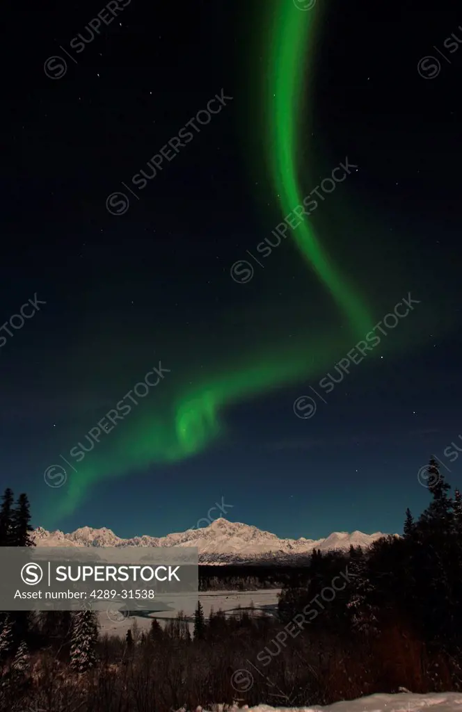 View of green Northern Lights Aurora borealis arching through the night sky over Denali State Park, Interior Alaska, Winter