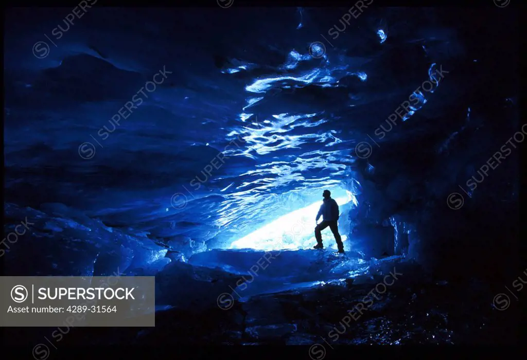 Man inside ice cave Skookum Glacier near Portage SC AK winter portrait