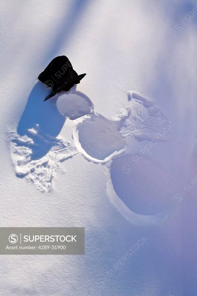 Snowman in forest making snow angel imprint in snow in late afternoon sunlight Alaska Winter