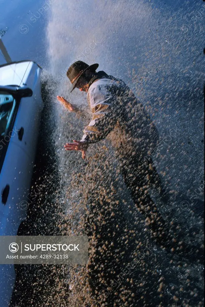 Car splashes man alongside road Southcentral Alaska spring portrait