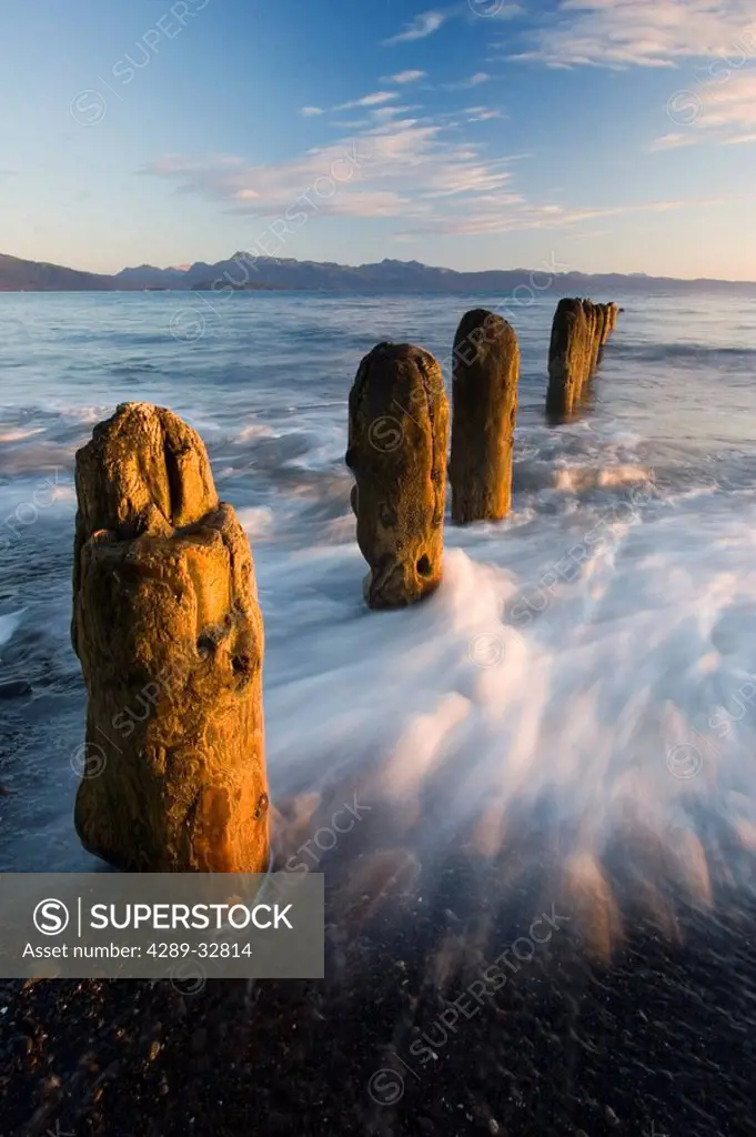 Surf rushing around old pilings along beach Homer Spit Kachemak Bay Alaska Summer evening blur motion