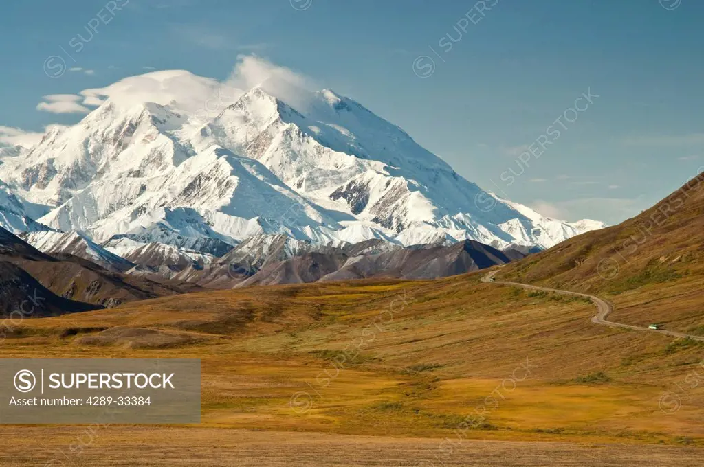 View of a visitor bus on the park road with Mt. McKinley towering in the background, Denali National Park & Preserve, Interior Alaska, Fall