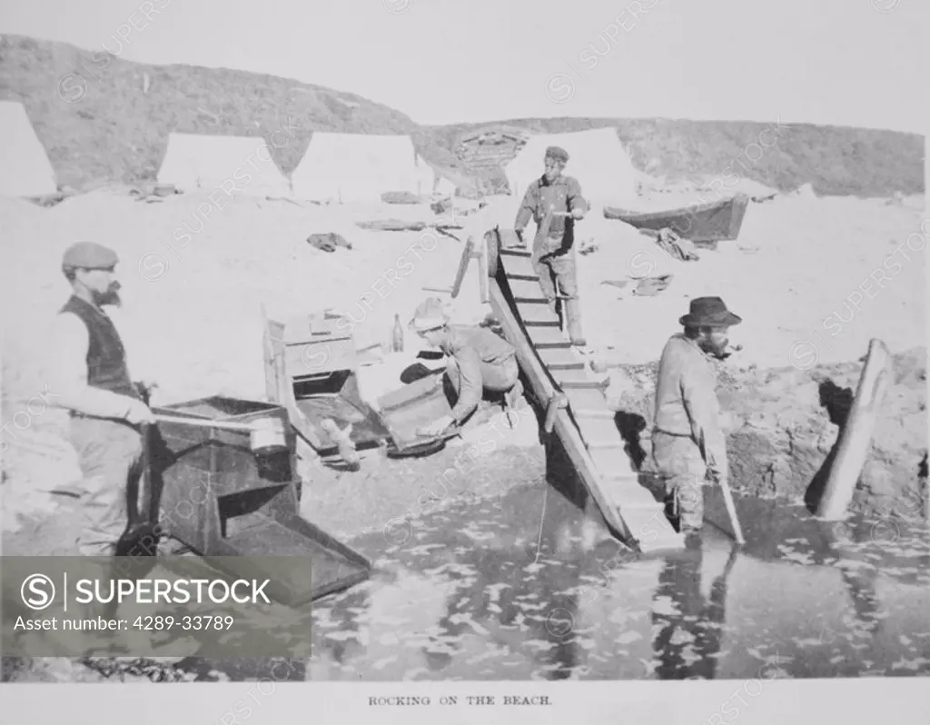 Historical image of gold miners using rocker boxes to look for gold on the beach summer Nome WE Alaska