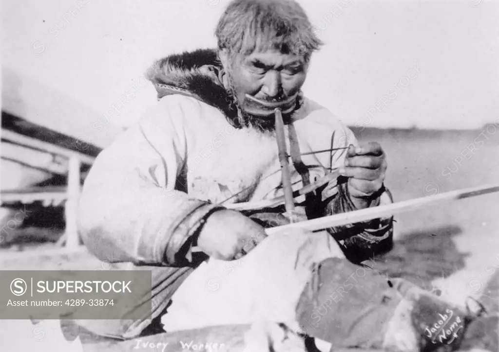 Historical image of a native man using a bow drill to work on ivory Nome WE Alaska