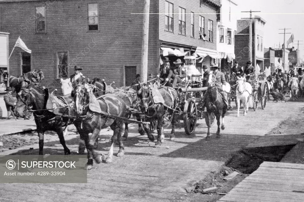 Parade of horse drawn wagons on street in Nome Summer WE Alaska