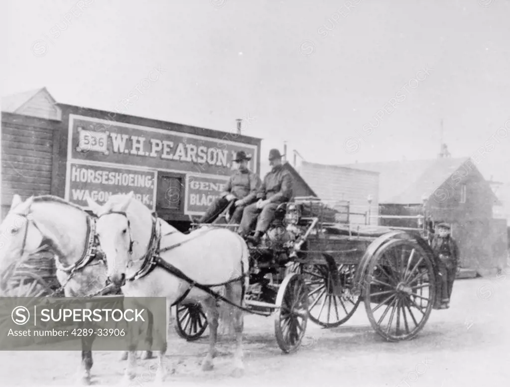 Historic image two men on a /nhorse drawn wagon with storefront behind them Nome Alaska