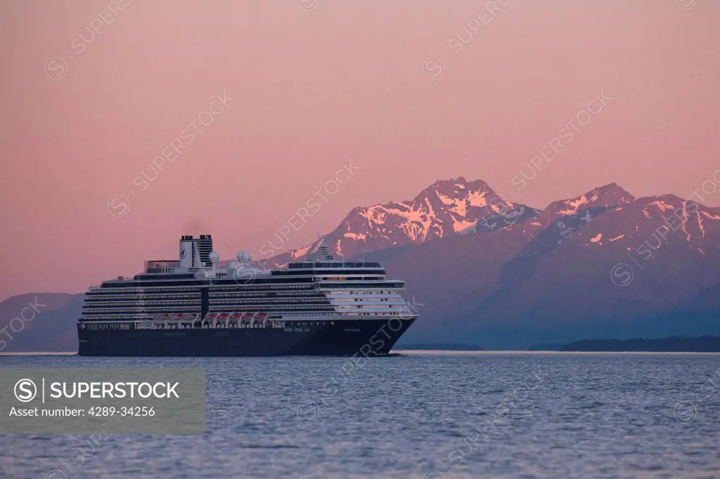 The Holland America Osterdam cruise ship travels through the Inside Passage at sunset with Eagle Peak and Admiralty Island in the distance, Southeast ...