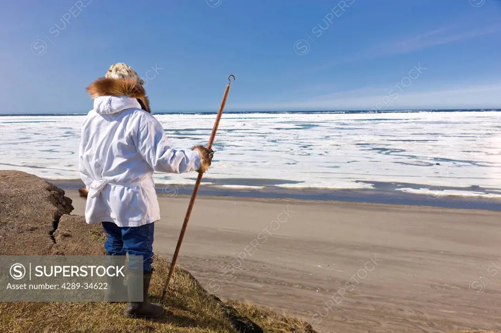 Portrait of a male Inupiaq Eskimo hunter wearing his Eskimo parka Atigi and seal skin hat and holding a walking stick at Old Utkeagvik original town s...