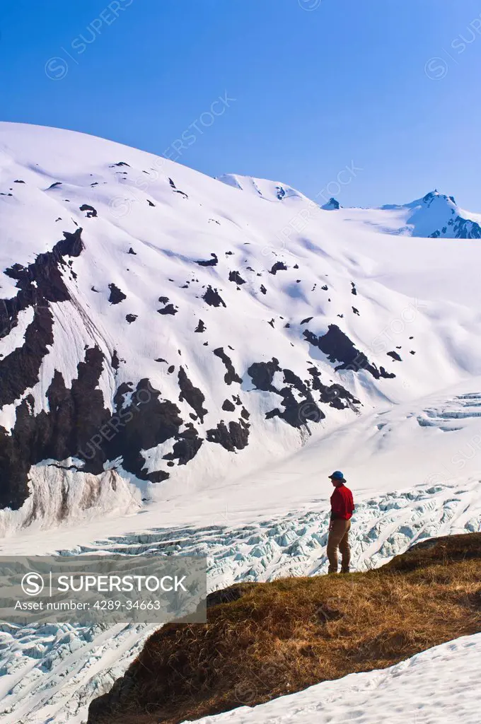 Male hiker overlooks Exit Glacier and the Harding Icefield from a ledge on Harding Icefield Trail, Kenai Fjords National Park, Kenai Peninsula, Southc...