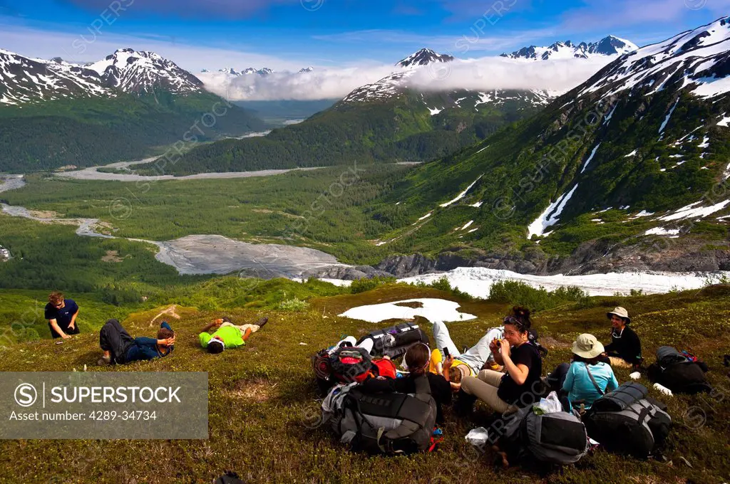 A group of teenage backpackers stop to rest on the Harding Icefield trail at Exit Glacier in Kenai Fjords National Park with the Chugach Mountains in ...