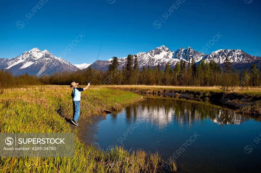 A young boy fishing on Rabbit Slough on a sunny spring day in the Matanuska_Susitna Valley, Southcentral Alaska