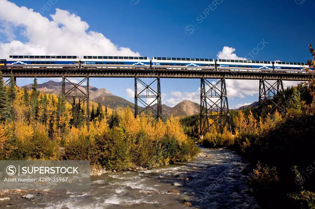 Riley Creek flows under the trestle as a northbound Alaska Railroad train and Holland America´s McKinley Explorer crosses a trestle, Southcentral Alas...