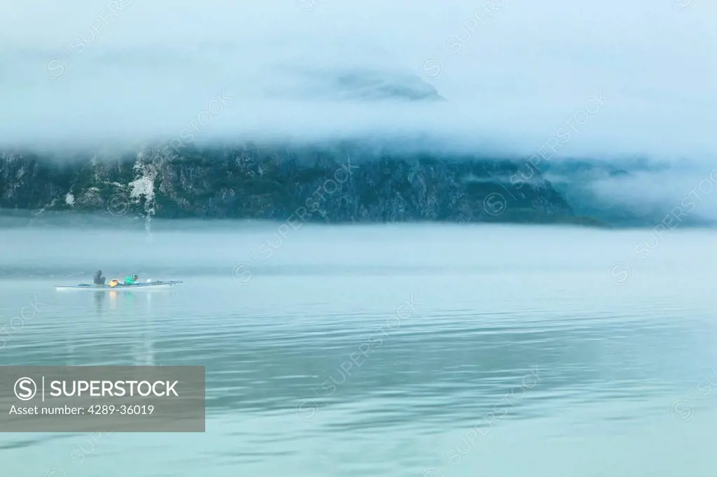 Kayakers paddling on a foggy day in Muir Inlet, Glacier Bay National Park & Preserve, Southeast Alaska, Summer