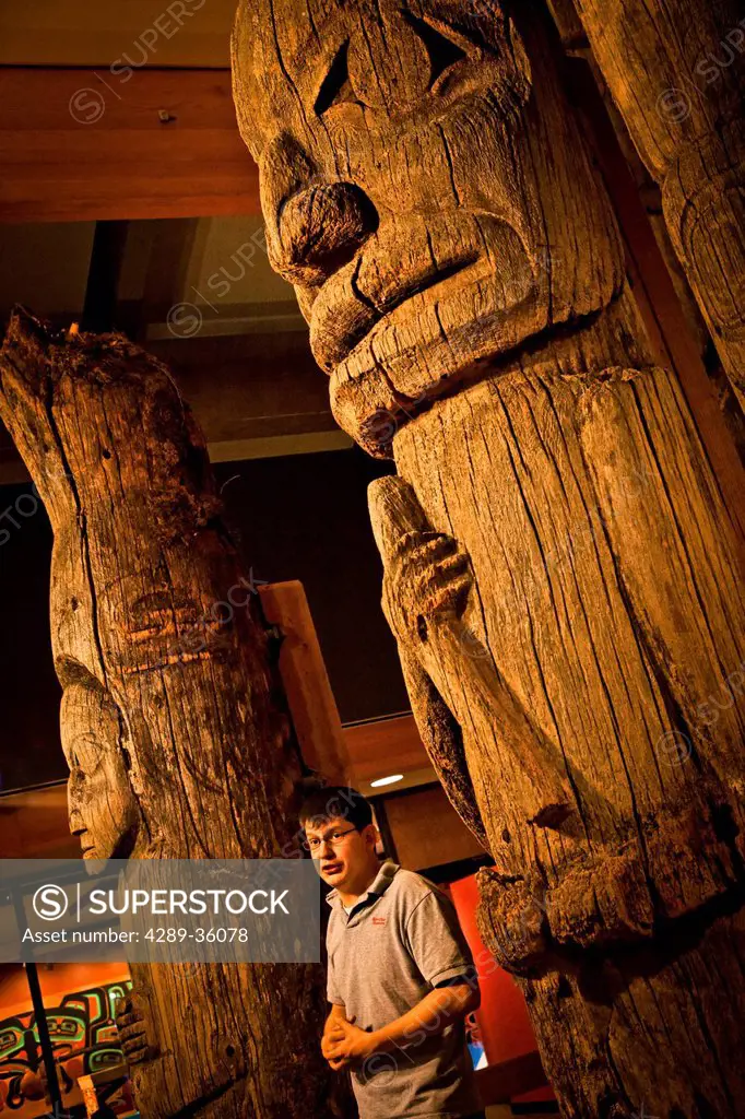 Native guide explaining the historic totem poles inside Totem Heritage Center, Ketchikan, Southeast Alaska, Summer