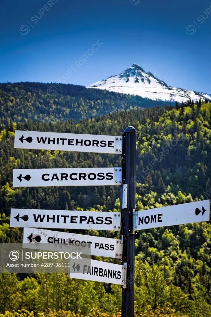 Close u p of a milepost Sign with a scenic view of a snowcapped mountain in the background, Skagway, Southeast Alaska, Summer