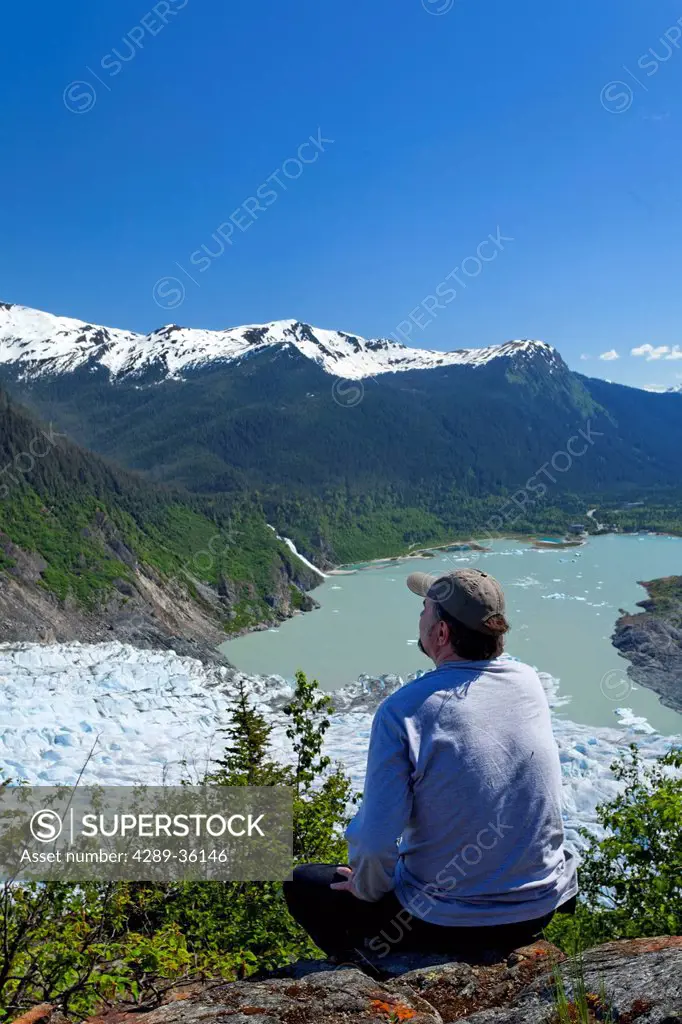 A male hiker looking down onto Mendenhall Glacier and Mendenhall Lake from West Glacier Trail, Juneau, Southeast Alaska, Summer
