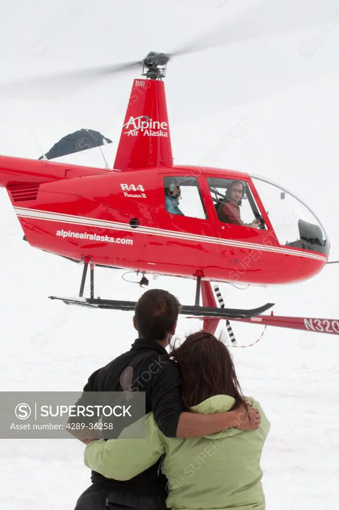 Tourists watch as a helicopter takes off from Punchbowl Glacier heading back to Girdwood, Southcentral Alaska, Summer