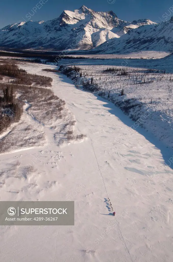Aerial view of a dog team mushing on the North Fork of the Koyukuk River in Gates of the Arctic National Park & Preserve with Boreal Mountain in the b...