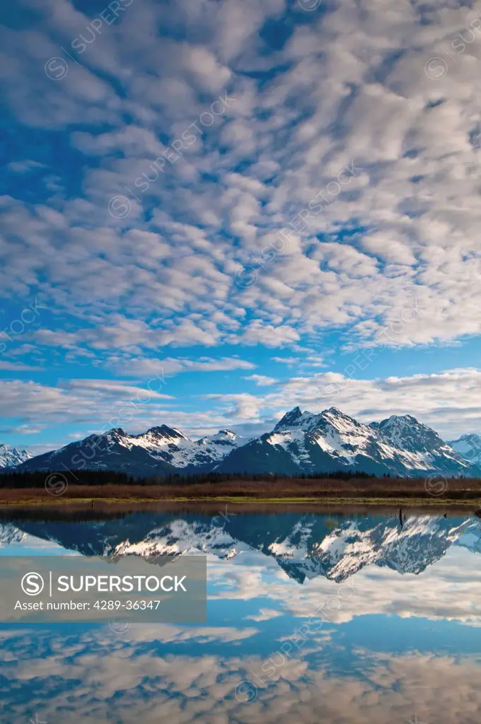 Alaganik slough reflecting the Chugach Mountains and cirrocumulus clouds in the morning, Chugach National Forest, Cordova, Southcentral Alaska, Spring