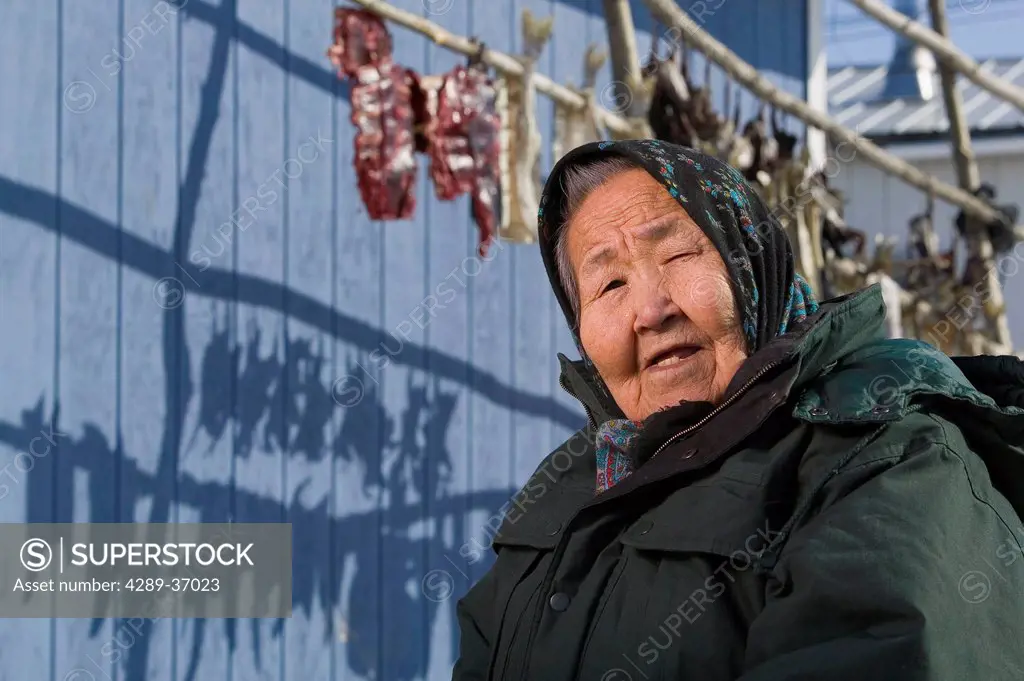 Portrait Of Elder Female Yupik Woman Sitting Outside Her House Near Fish Drying Racks Akiachak We Alaska