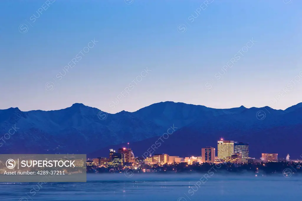 The Anchorage Skyline Before Dawn With Fog Rising From The Waters Of Cook Inlet As Seen From Earthquake Park, Southcentral, Alaska