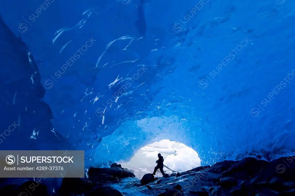 Photographer Carrys His Camera And Tripod Into The Entrance Of An Ice Cave At Mendenhall Glacier Near Juneau. Summer In Southeast Alaska.