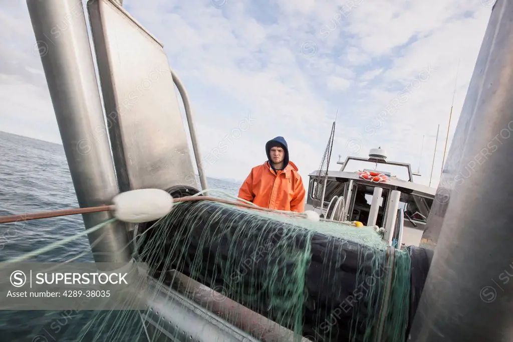 A Young Deckhand Watches And Waits For Fish As The Gillnet Is Pulled On Board His Bowpicker While Commercial Salmon Fishing On The Copper River Flats;...