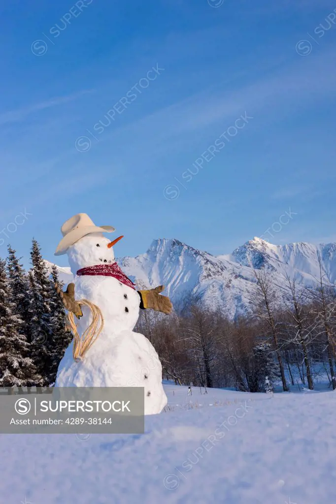Snowman dressed up as a cowboy standing in front the chugach mountains in winter;Palmer alaska usa