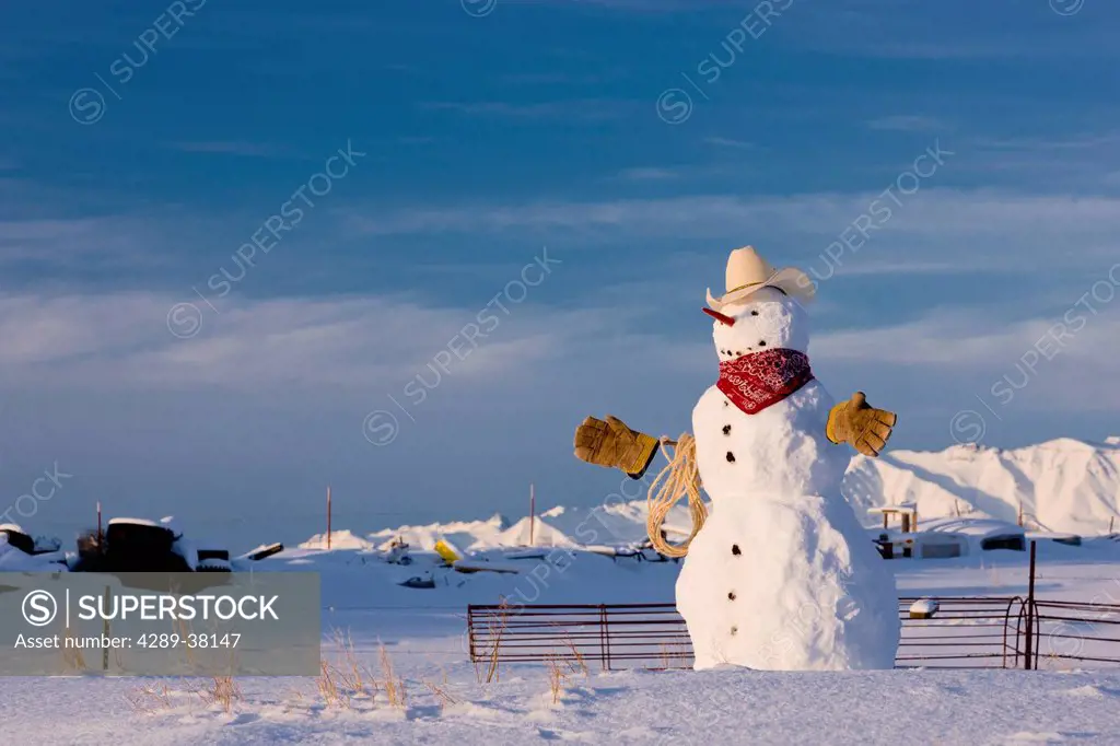 Snowman dressed up as a cowboy standing in front of a fence on a farm in winter;Palmer alaska usa