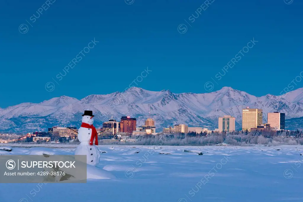 Snowman on frozen tidal flats with downtown anchorage skyline in the background knik arm;Alaska usa
