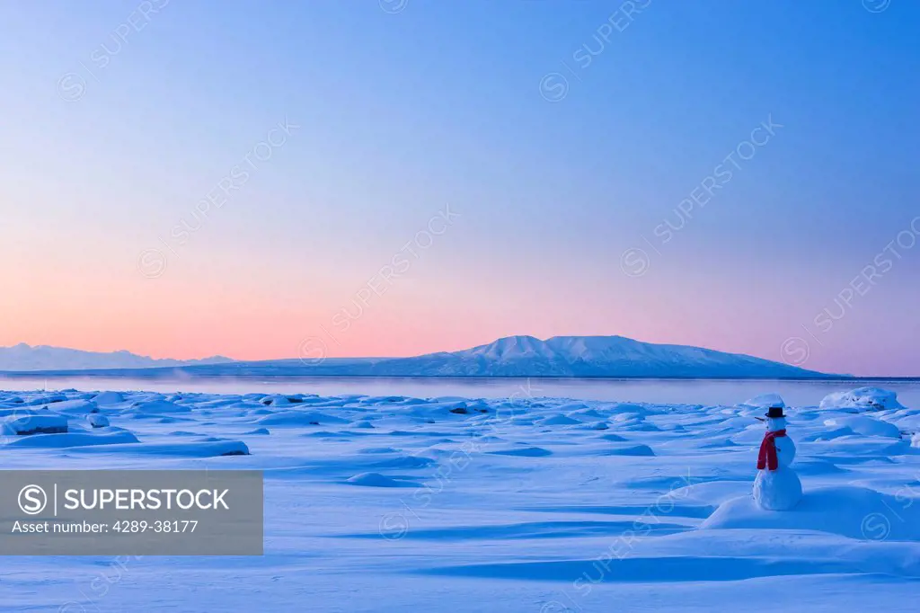 Snowman standing on the snow covered tidal flats of knik arm at sunset with mt. susitna tony knowles coastal trail;Anchorage alaska usa