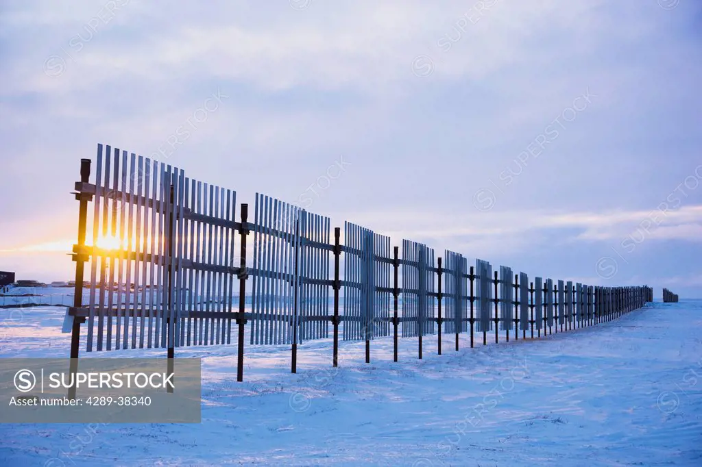 Sun setting behind a snow fence;Barrow alaska united states of america