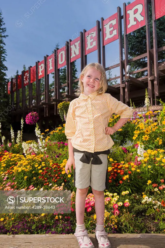 5 year old Caucasian girl standing in front of the entrance to Pioneer Park amusement park, summer, Fairbanks, Interior Alaska, USA