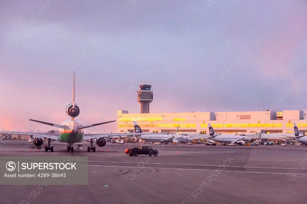 Sunset light falls on Ted Stevens International Airport, view from the Tarmac, early Spring, Anchorage, Southcentral Alaska, USA.