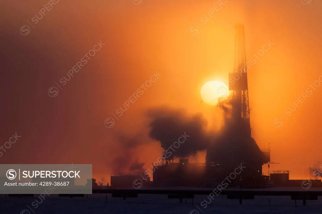Doyon Drilling Rig and well houses on Drill Site 7 at sunset in the Prudhoe Bay Oil Field, North Slope, Arctic Alaska, Winter