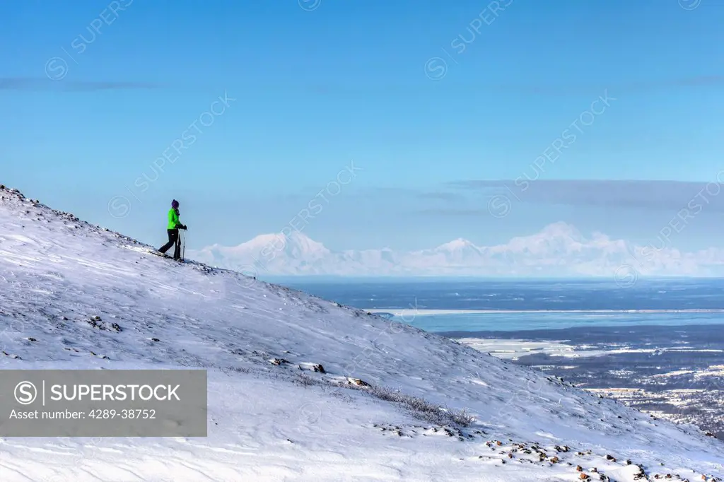 Woman snowshoeing on Blueberry Hill at the Glen Alps area of Chugach State Park with Mt. McKinley (Denali), Mt. Hunter, and Mt. Foraker in the backgro...