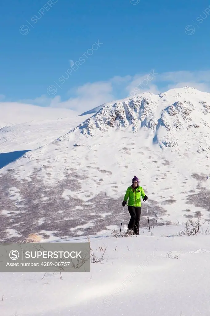Woman snowshoeing at the Glen Alps area of Chugach State Park on a sunny winter day, Anchorage, Southcentral Alaska