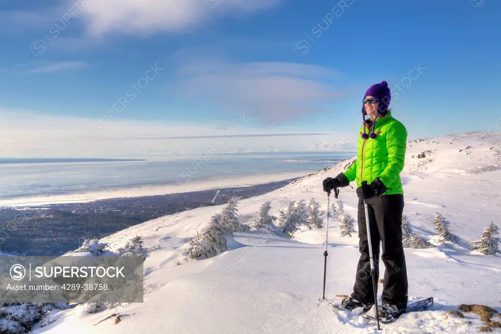 Woman snowshoer taking in the view of the Chugach Mountains from Blueberry Hill at the Glen Alps area of Chugach State Park, Anchorage, Southcentral A...