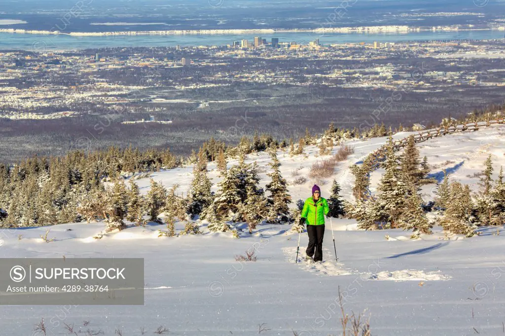 Woman snowshoeing at the Glen Alps area of Chugach State Park overlooking Anchorage on a sunny winter day, Southcentral Alaska, HDR